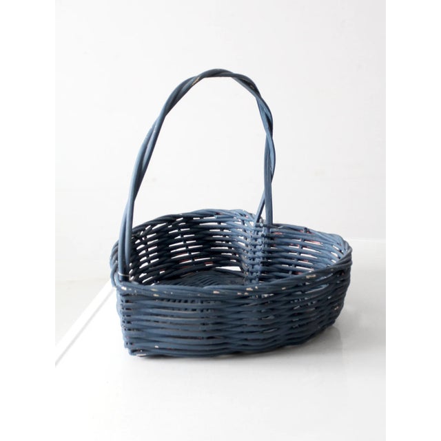 This vintage wicker basket features a heart-shaped silhouette and a twisted handle. The weathered blue finish adds a soft,...