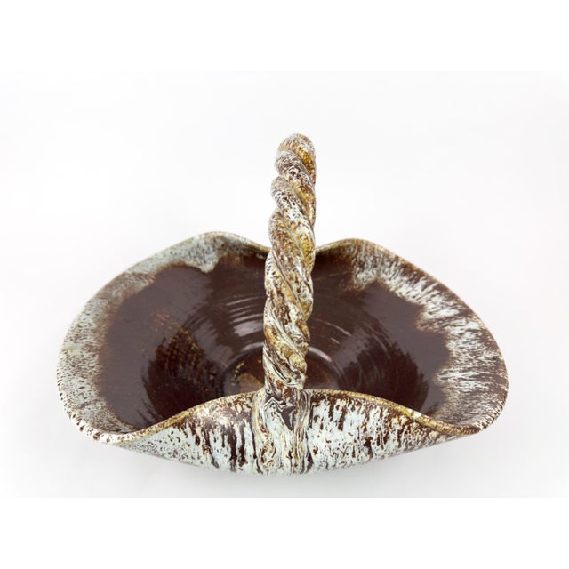 A collector-grade mid-century ceramic basket by Accolay, France. This sculptural piece features a broad flared body and a...