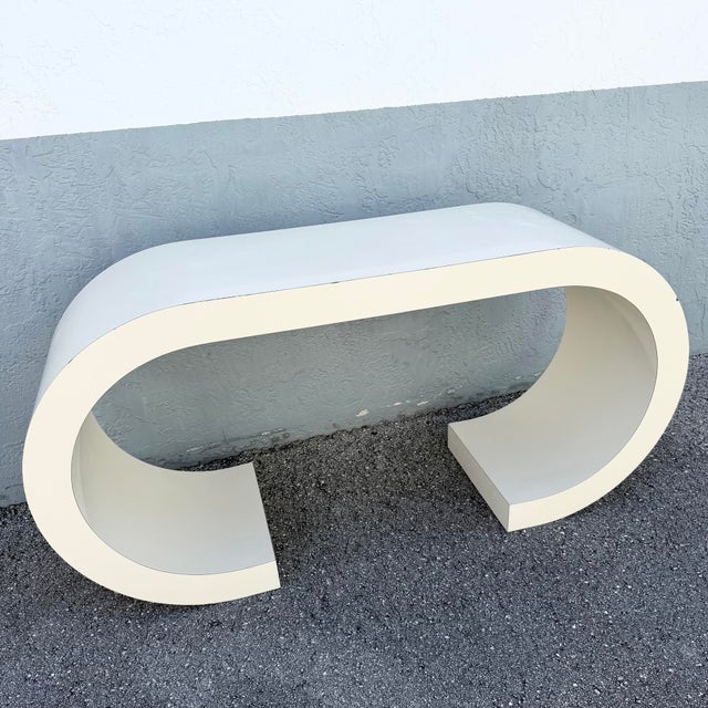 Striking vintage Postmodern console table featuring a dramatic continuous scroll silhouette finished in cream gloss...