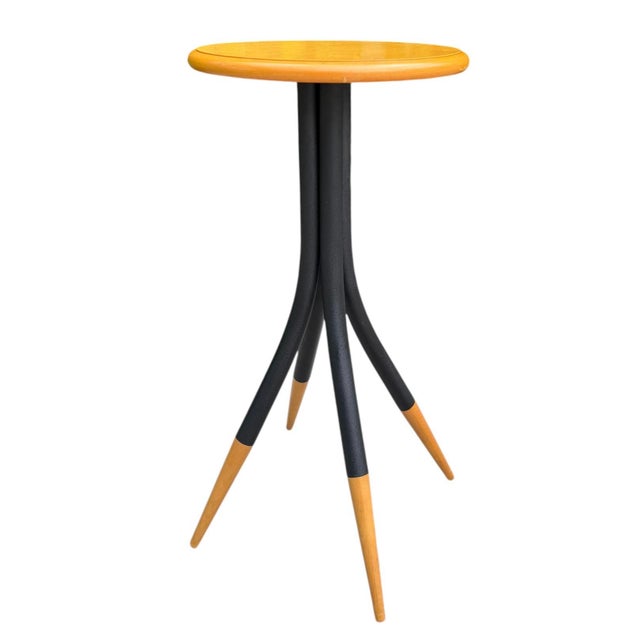 A distinctive vintage sculptural accent table featuring a warm-toned hardwood top supported by four gracefully curved...