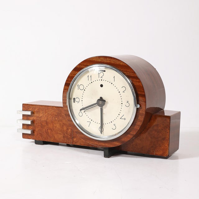This Art Deco Machine Age electric clock, crafted in burled walnut with rectilinear aluminum banded detailing, is a...