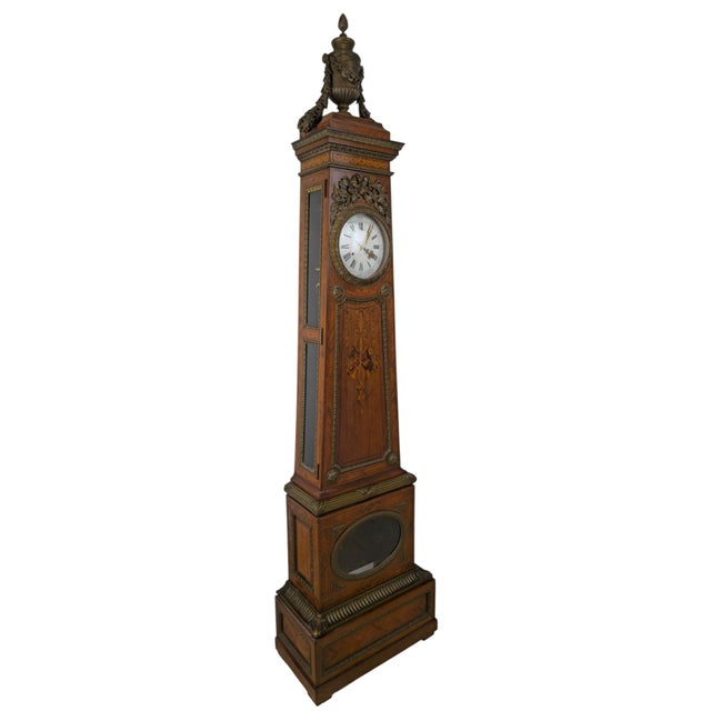 The case is veneered in herringbone parquetry with a central marquetry trophy of musical instruments, ribbons and hanging...