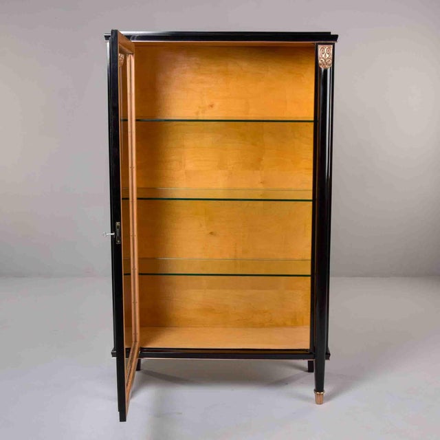 Striking single-door vitrine featuring high-gloss black lacquered exterior contrasting with warm maple interior. Three...