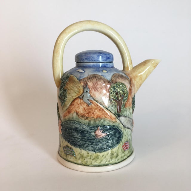 A Laura Wilensky studio ceramic teapot with applied and relief decorations depicting bunnies at home and swimming in a...
