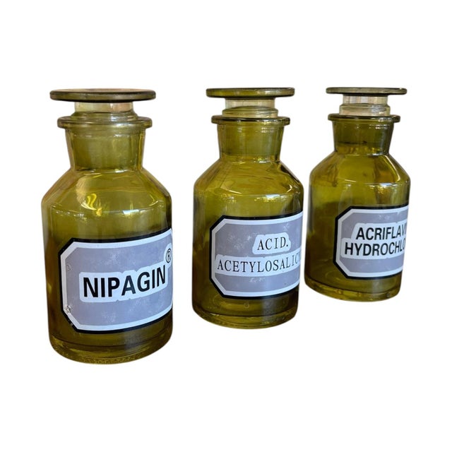 Set of three vintage apothecary or pharmacy bottles made from olive green toned glass, each fitted with a matching ground-...