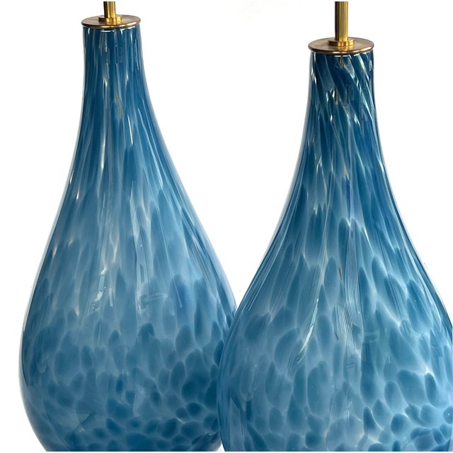 each shapely lamp of hand-blown sky blue dappled glass all raised on a brass and lucite circular base; height: 17.75" (top...