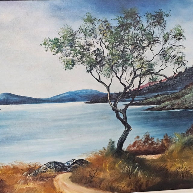 This oil on canvas painting depicts a serene landscape of a mountain lake. It is beautifully presented in a carved wood...