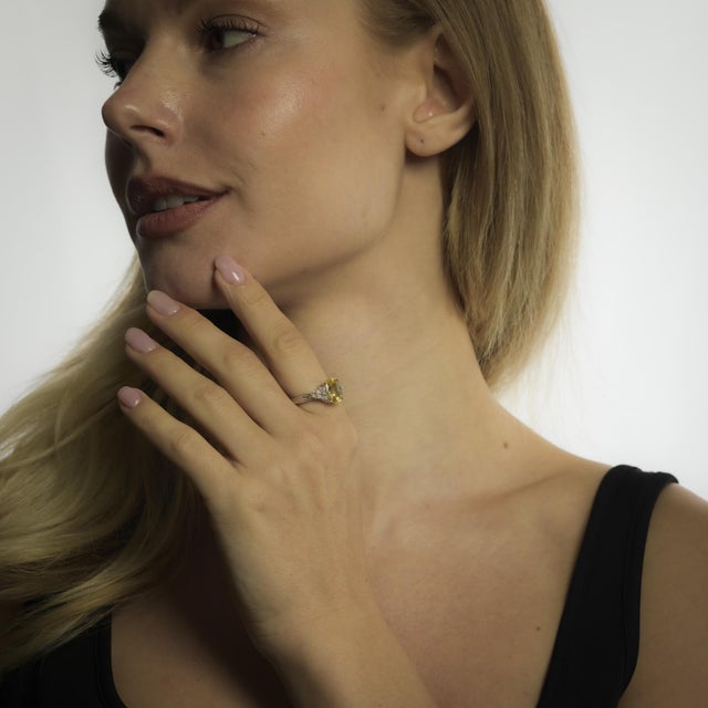 A vibrant 3.90 carat Ceylon yellow sapphire radiates warmth in this Mid Century ring, accented by tapered diamond...