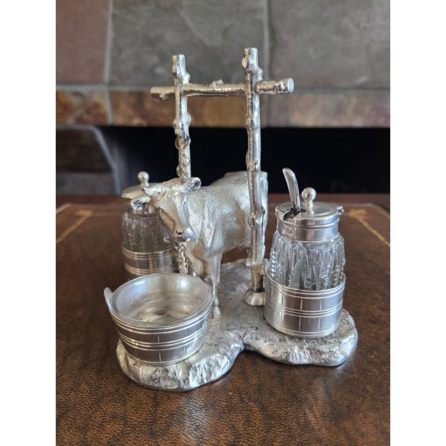 Stunning late 19th century silver plated cruet set featuring a cow tethered to a post. Includes two cut glass condiment...