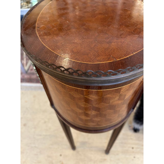 Elegant oval marquetry end table having 3 drawers, tapered legs, brass gallery and decorative bronze mounts.