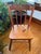 Wooden side chair with a spindle back and a solid saddle seat. Three turned spindles rise to a wide top rail with a cutout...