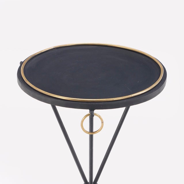 Each table features a painted iron top accented with bronze ring detailing encircling the surface and three hanging rings...