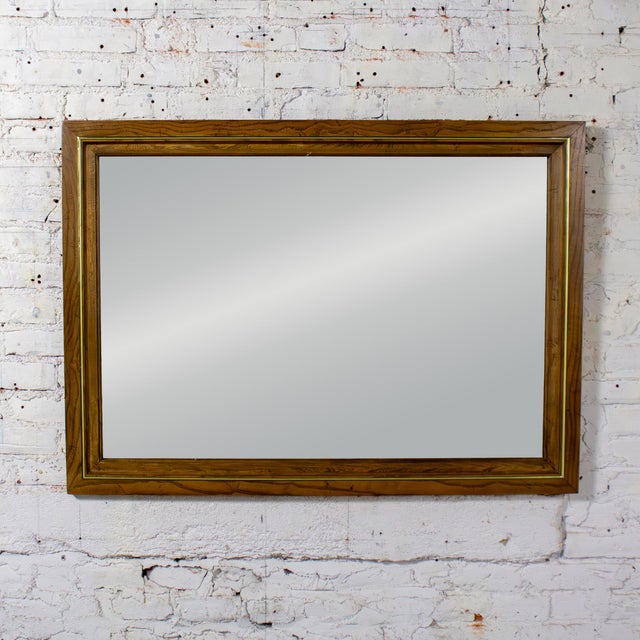 Marvelous vintage wall mirror by Thomasville composed of a rectangular oak frame with a brass plated decorative detail....