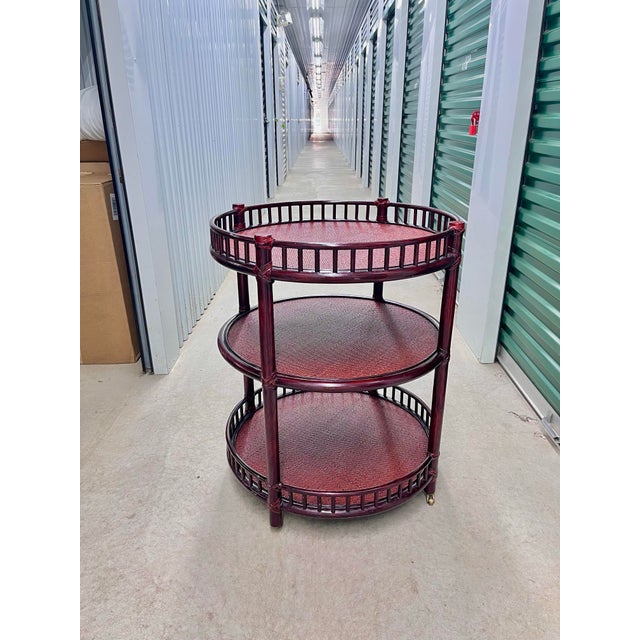 A generously proportioned three tiered table on brass casters by McGuire made of bamboo, woven rattan, and rawhide lace....