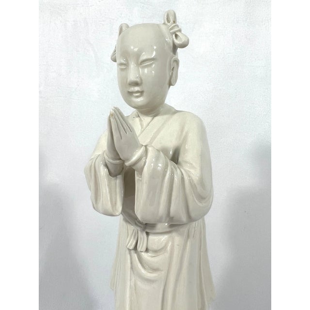 Attractive figurine of a young Chinese girl made from white porcelain called Blanc de Chine. Posing on a base of waves in...