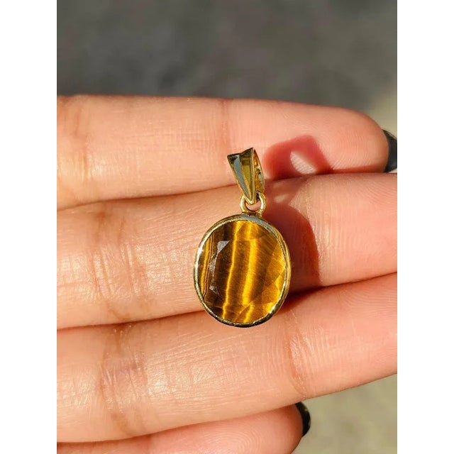 This is part of Chairish’s Fine Jewelry assortment. Tiger's eye pendant in 18K Gold. It has a oval cut gemstone that...