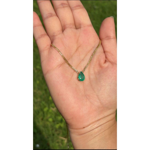 This solitaire pendant necklace features a 1.63 carat pear-cut emerald set in 14K yellow gold. The emerald measuring...