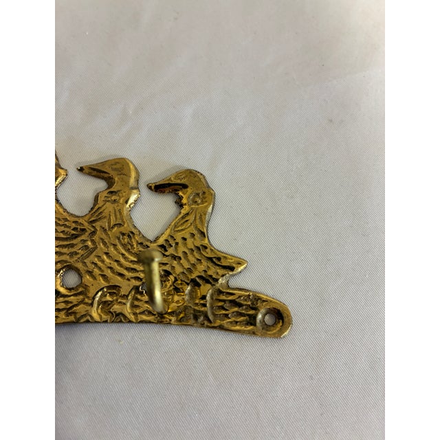 A charming vintage brass wall hook with three ducks in a row, their bodies richly textured to suggest feathers. Two small...