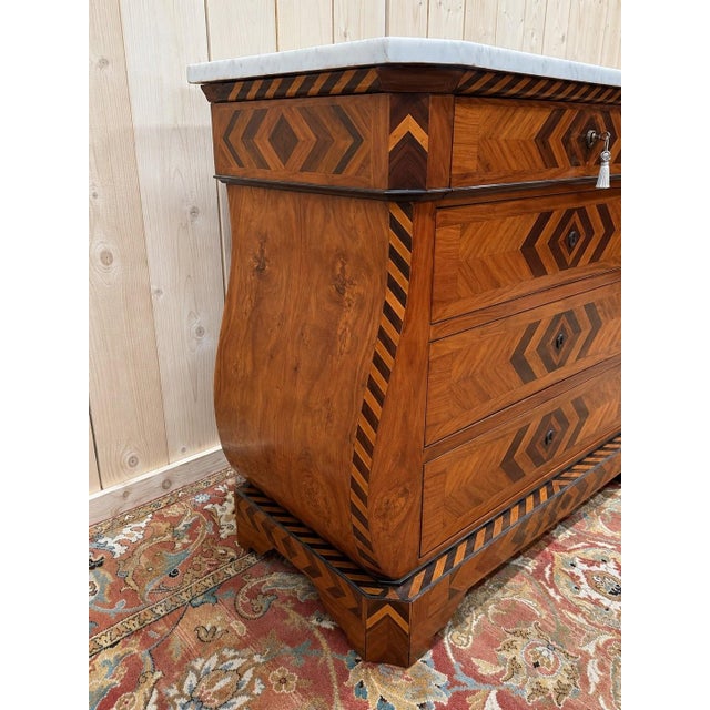 A bombé commode in the swiss style, dating from the 19th century, with a tomb-like silhouette and curved sides. the front...