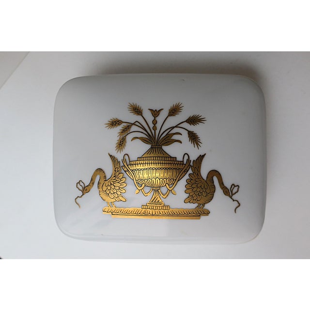 A beautiful porcelain box with urn vase, sheaf-of-wheat, and bird design, circa mid-20th century. Box lid with gold urn...