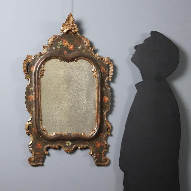 Lacquered and painted wood freestanding mirror. Frame with gilded Rocaille carvings, floral arrangements painted across...