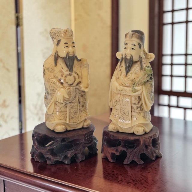 Pair of Chinese scholar or deity figures executed in resin material with finely engraved robe decoration highlighted in...