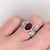 A rubellite tourmaline sits in a saturated raspberry red at the heart of this solid 14K white gold ring, framed by 116...
