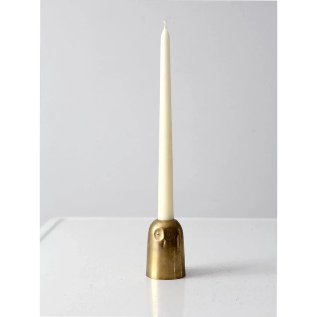 This is a mid 20th century brass owl candlestick holder. The rounded brass holder holes a standard candle taper.