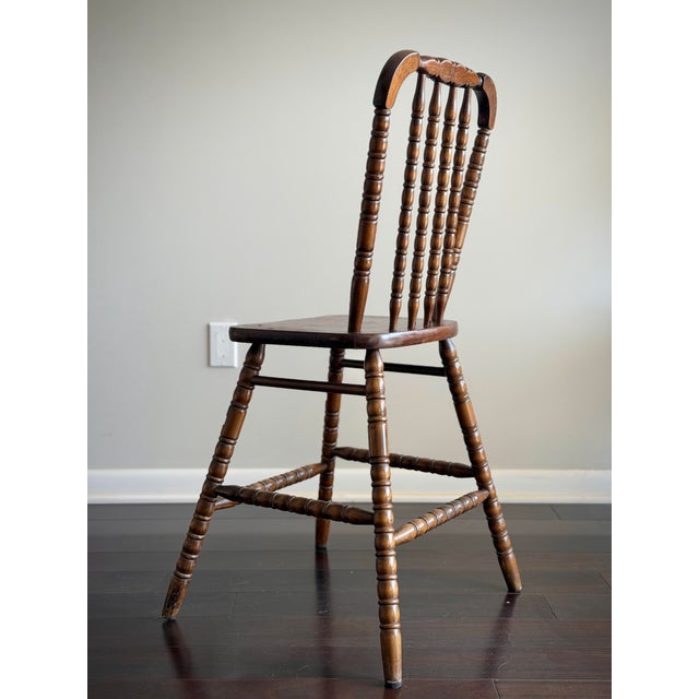 A charming antique English tavern chair dating to the late 19th or early 20th century, featuring a sculpted spindle back,...
