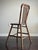 A charming antique English tavern chair dating to the late 19th or early 20th century, featuring a sculpted spindle back,...