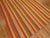 20th century Turkish Kilim with a striped motif in orange, pinks, reds, yellows, teal and brown.