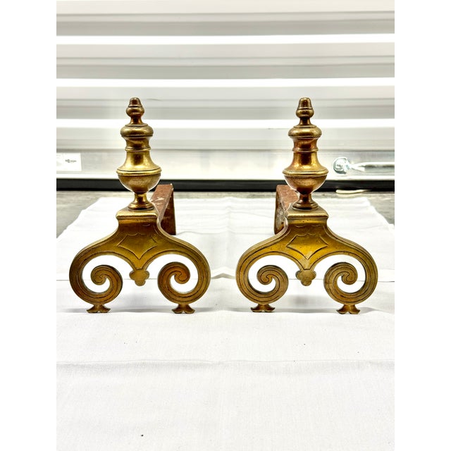 Antique pair of 17th-century fireplace andirons with turned brass finial tops and scrolled brass feet featuring an...