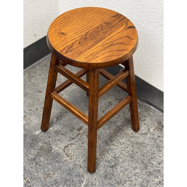 Design Plus Gallery presents a Vintage Wooden Stool. It has a round seat, tapered legs, and square stretcher supports. The...