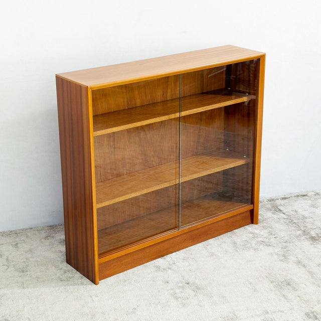 A low bookcase by gibbs furniture, with two sliding glass doors across the full front. It's a simple box, and the timber...