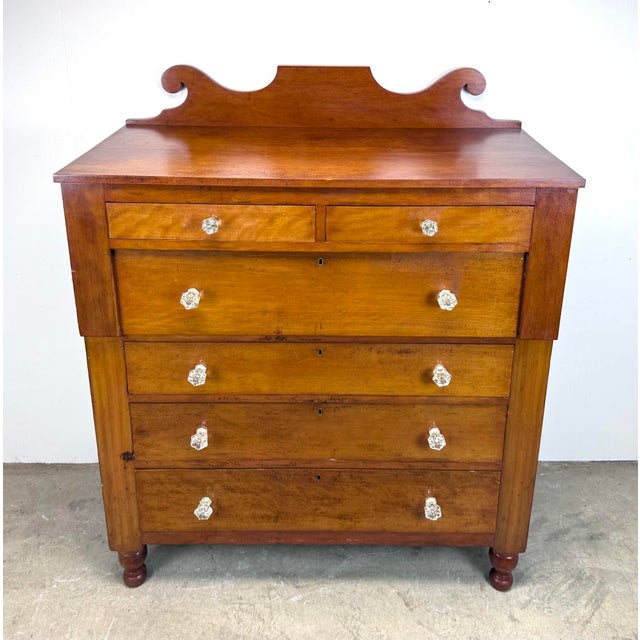 An impressive mid 19th century cherry wood chest of drawers with glass drawer pulls and scroll top. Professionally...