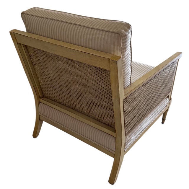 Well-made lounge chair featuring a light wood frame with woven cane panel sides and back, paired with soft beige...