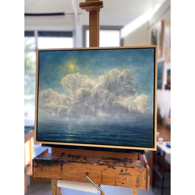 The artwork depicts a serene seascape, where soft, billowing clouds float above a tranquil ocean, illuminated by a gentle...