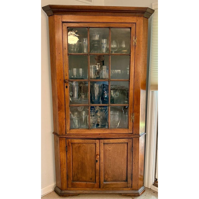 A 19th century Federal corner cupboard cabinet walnut with a warm honey-toned patina, a simple stepped cornice, single...