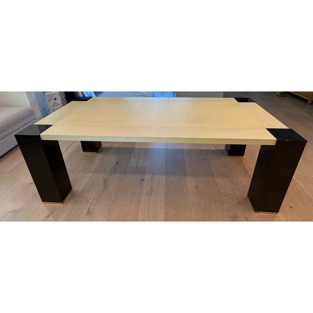 An Armani Casa dining table with goatskin parchment top over black lacquered wooden legs with brass detailing, made in...