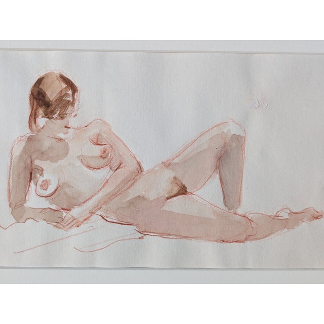 Confident sanguine line work with soft watercolor wash - a classic life drawing session captured on generous paper. The...
