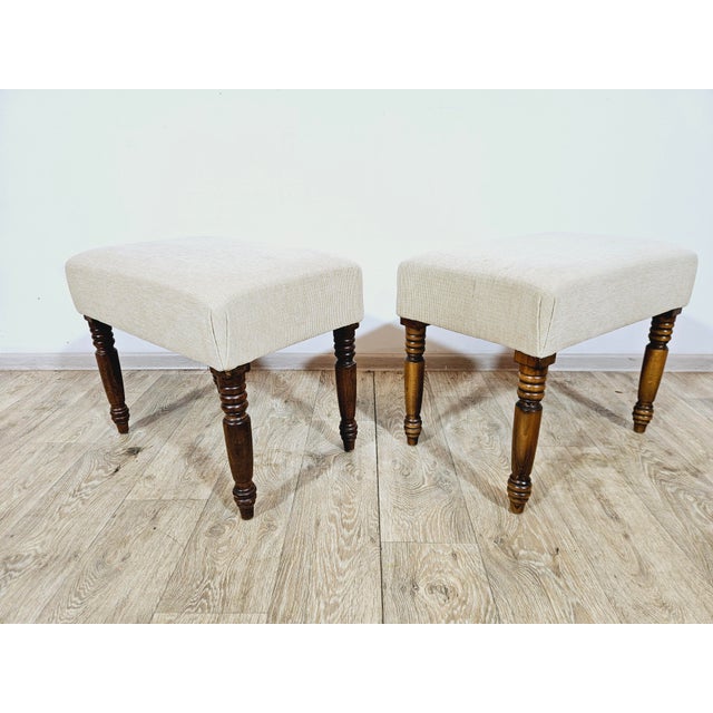 A set of two elegant poufs on decorative, turned legs made of walnut in the English style. The seats are finished with a...