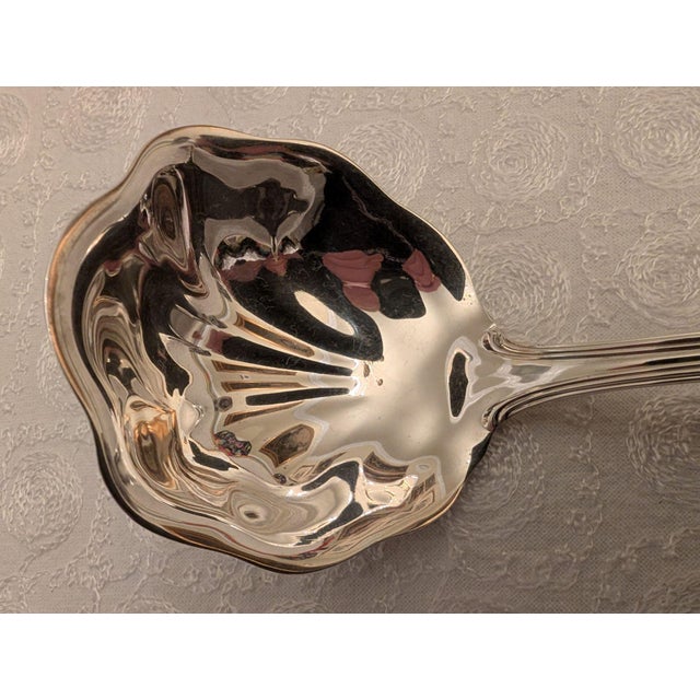 An all-purpose sterling silver sauce ladle by Towle in the "Benjamin Franklin" pattern of a traditional shell design...