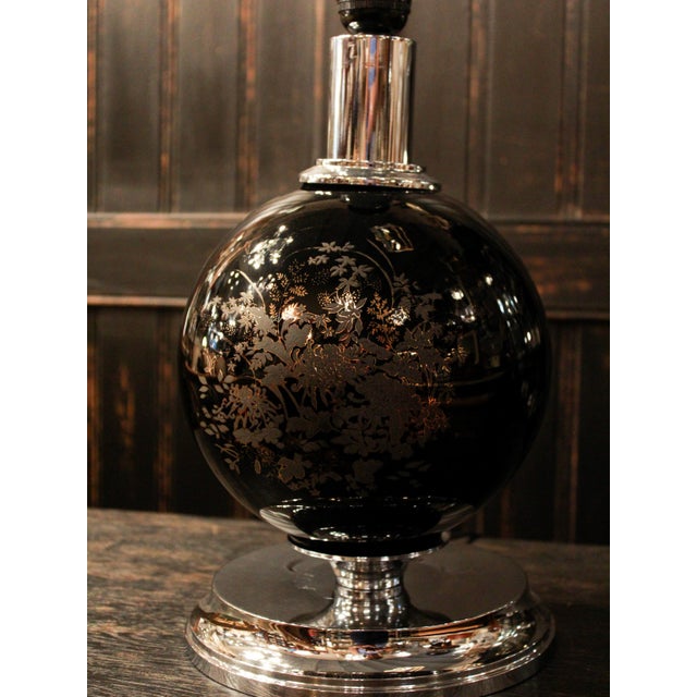A sophisticated Italian table lamp crafted in deep black porcelain, featuring delicate floral detailing and a striking...
