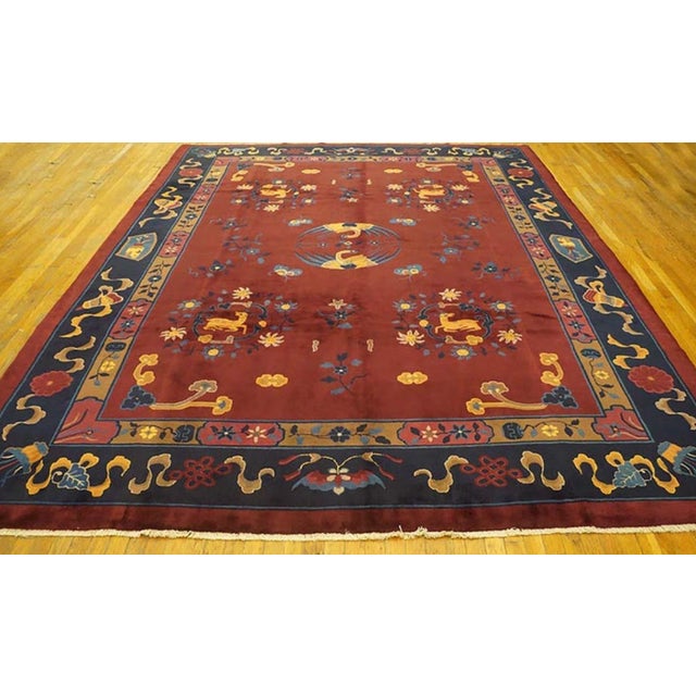 Antique Chinese Art Deco rug with a red background and navy border.
