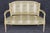 Graceful, refined, and unmistakably elegant, this exceptional French Louis XVI style painted and parcel-gilt settee is a...