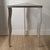 A striking sculptural side table featuring three individually worked metal legs with hammered detailing and irregular cut...