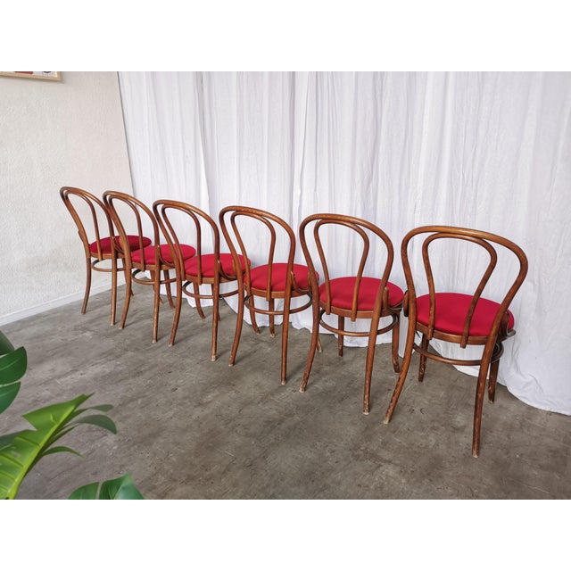 Set of 6 vintage bentwood dining chairs from the 1970s. The chairs feature a classic curved wooden frame in dark brown...
