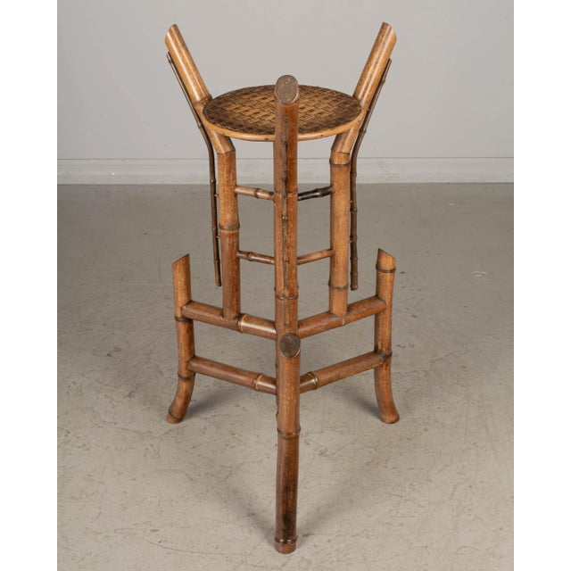 A Mid Century French bamboo plant stand or pedestal composed of a large center pole with sturdy tripod base and woven...