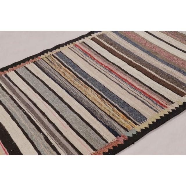Handwoven in wool and originating circa 1950-1960, this 4x7 vintage Persian kilim rug is a masterfully curated tribal...