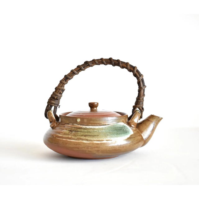 A vintage hand thrown red clay tea pot with a rattan handle, probably a Japanese form of bankoware, possibly Chinese, mid-...